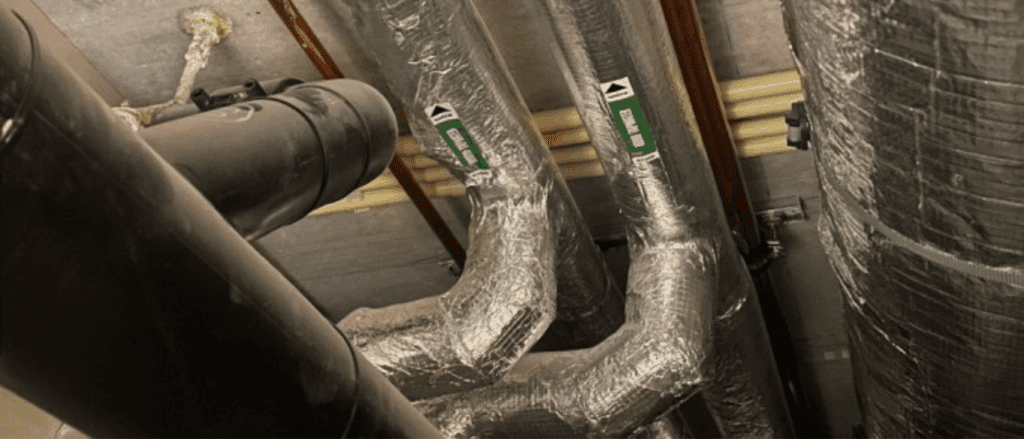 Geïsoleerde leidingen met aluminiumfolie en groene waarschuwingsstickers