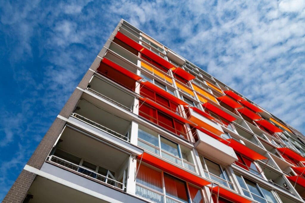 Block of Flats apartment house in Rotterdam Netherlands with Balconys, windows and orange awnings. Background with elements of a typical building from the Sixties and Seventies from frog perspective.