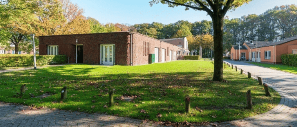 Laagbouw zorgwoningen op een groen terrein met gazon en bomen
